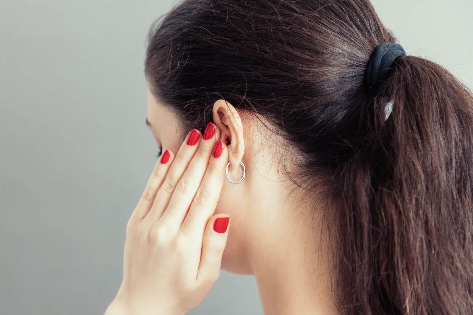 Side view of woman pressing on her ear