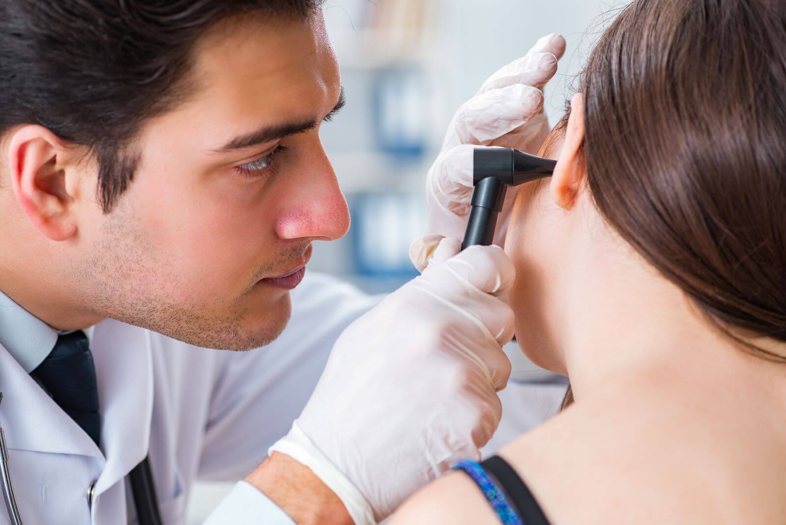 Audiologist examining patient ear