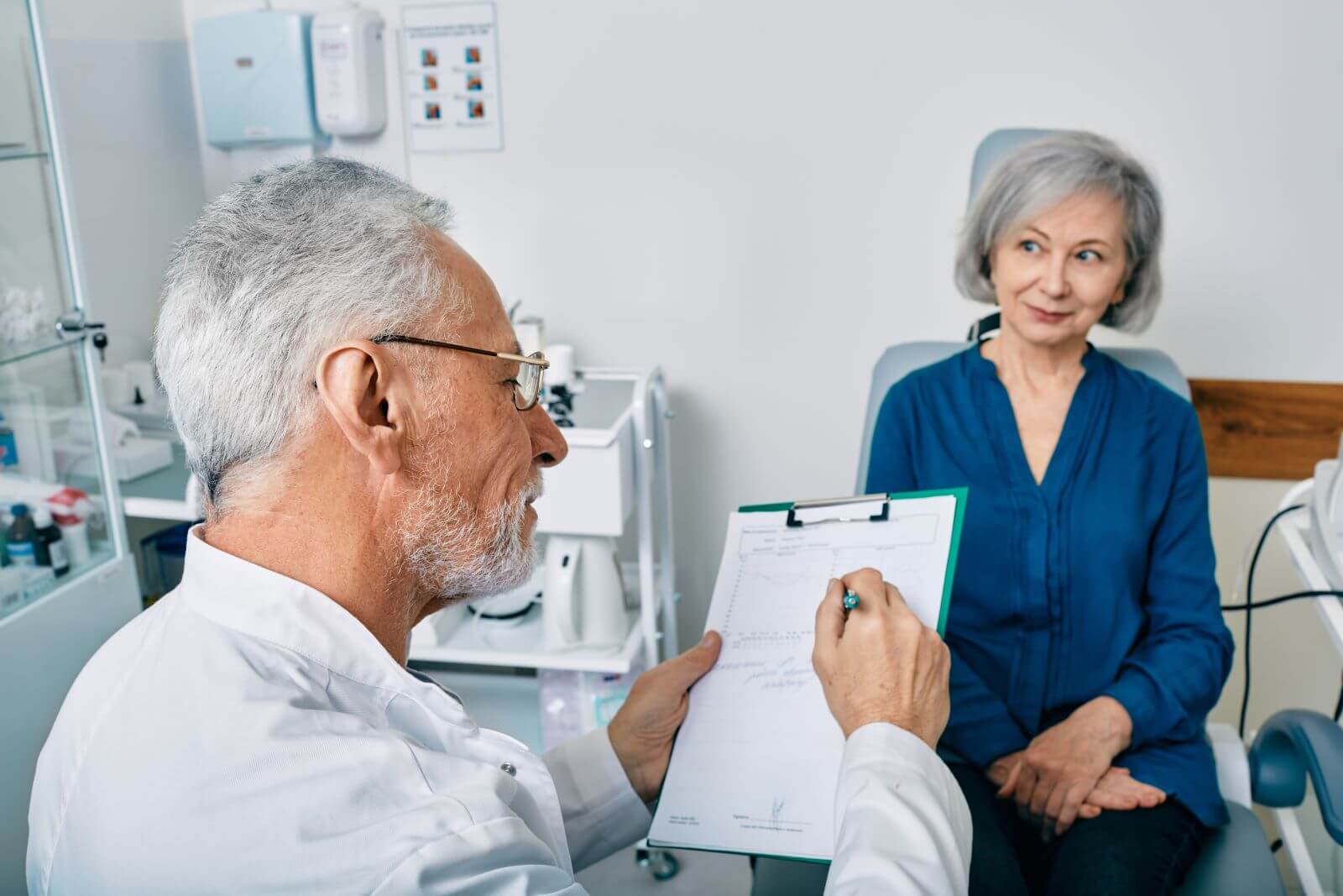 Audiologist filling out patient paperwork with patient