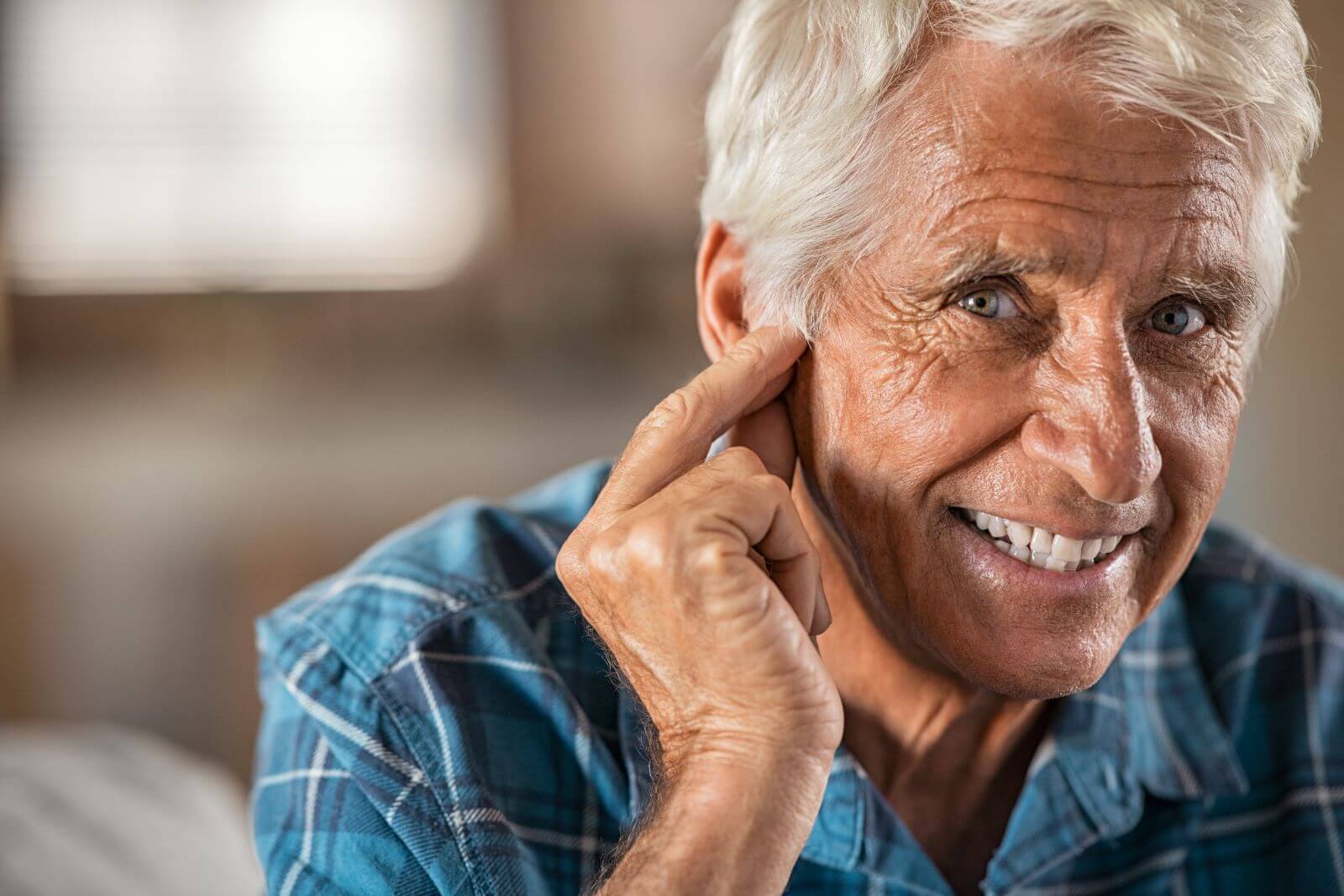 Senior man with hearing trouble holding his fingers to his ear