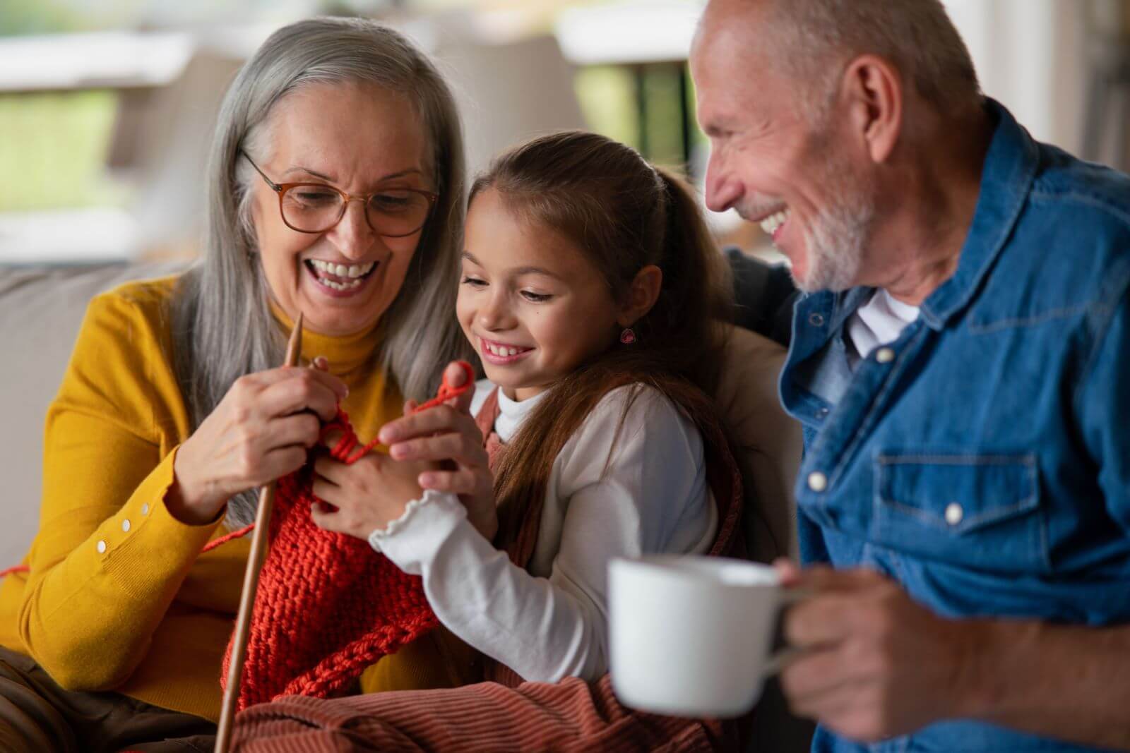 Little girl learning to knit with her grandparents