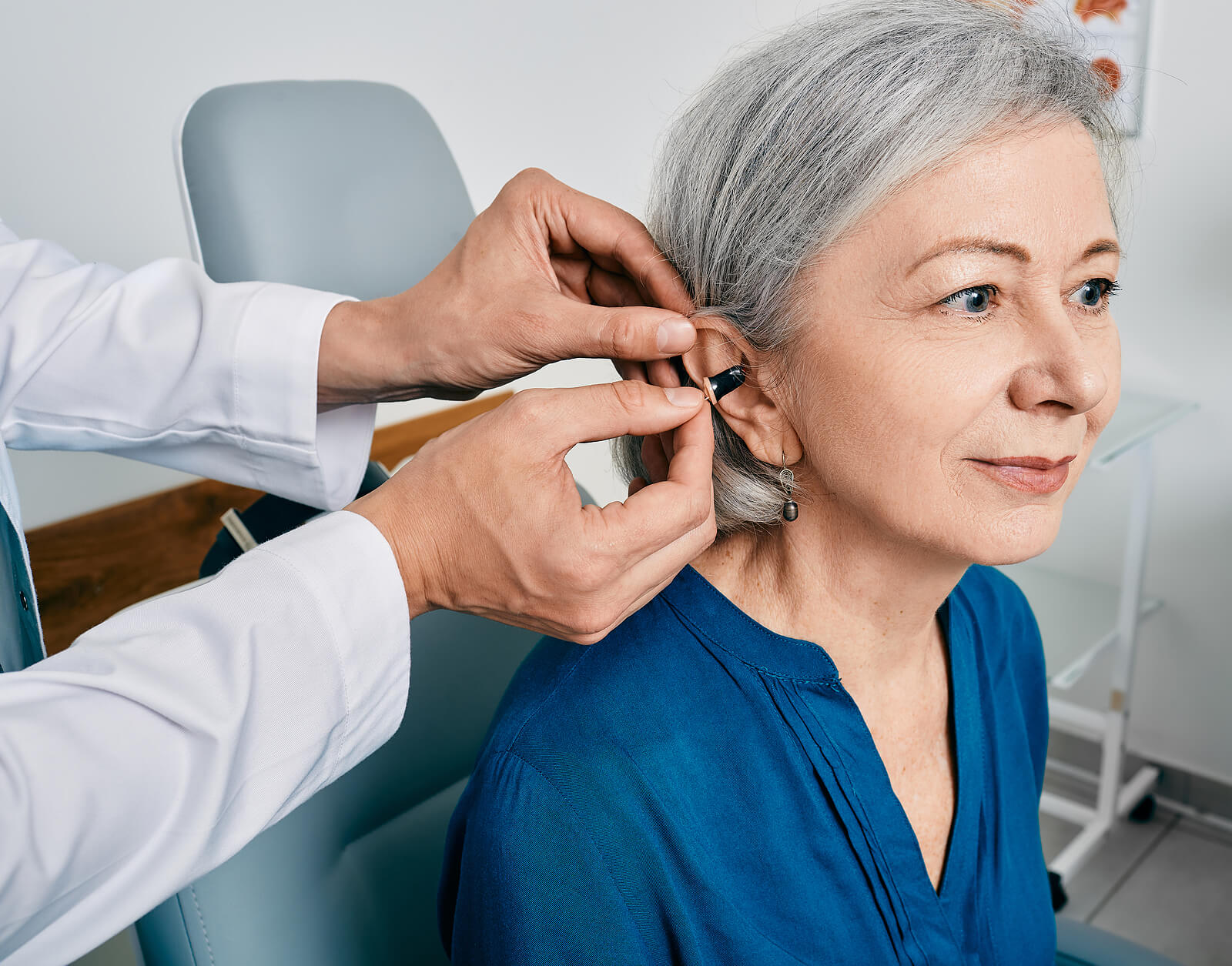 Senior woman having hearing aid fitted by audiologist