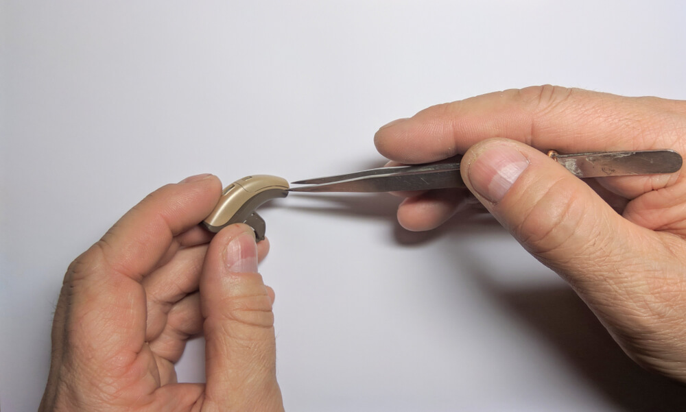 Two hands repairing a hearing aid